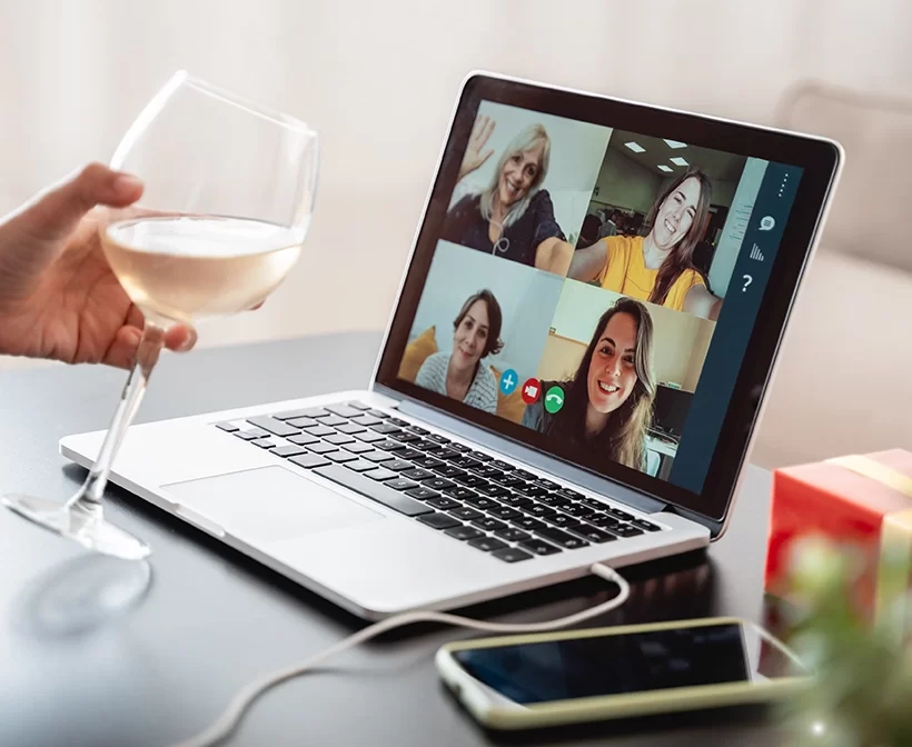 Happy woman celebrating on Christmas virtual video call party cheering with wine online at home