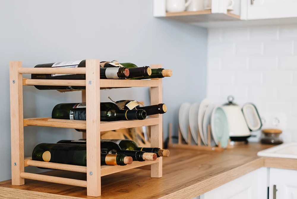 Wooden Wine Shelves With Bottles On The Table In Modern Kitchen.